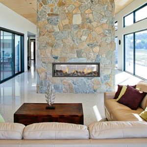 Elegant living room with a Heat & Glo Mezzo Series fireplace set in a stone wall, adding warmth and style with modern gas log fires for homes