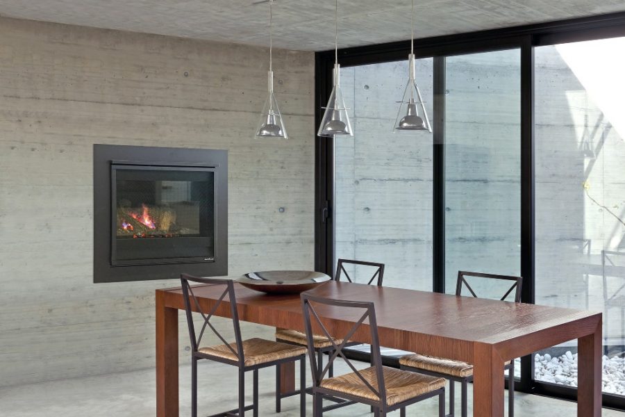 A dining table with chairs positioned in front of a Heat & Glo 3X fireplace, creating a cosy atmosphere