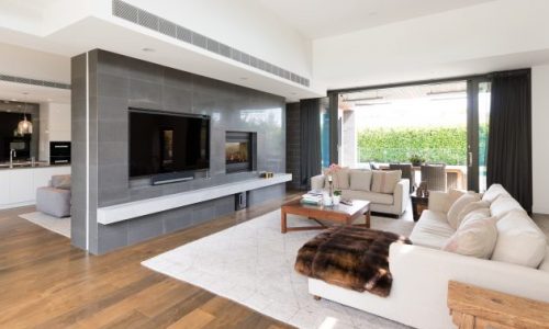 Modern living room with wooden floors, large TV, and Heat & Glo ST-HVBI fireplace, one of the best gas log heaters for autumn