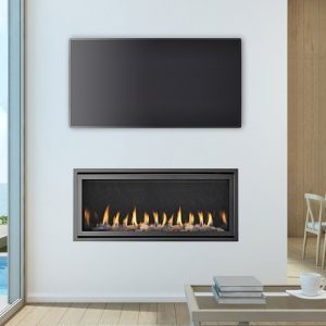 A modern Heat & Glo SLR-X flue gas fireplace in a living room with a stunning view of the ocean through large windows, one of the best gas log heaters for autumn
